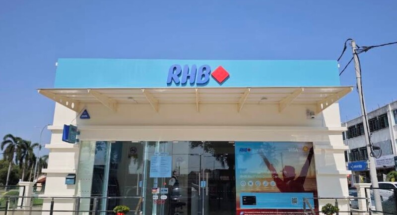 Pandangan hadapan cawangan bank RHB Parit Buntar dengan papan tanda logo biru dan merah di bawah langit cerah
