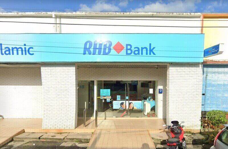Pandangan luar cawangan RHB Bank yang terletak di Bekok dengan papan tanda biru muda, bahagian hadapan bata putih dan pintu masuk kaca