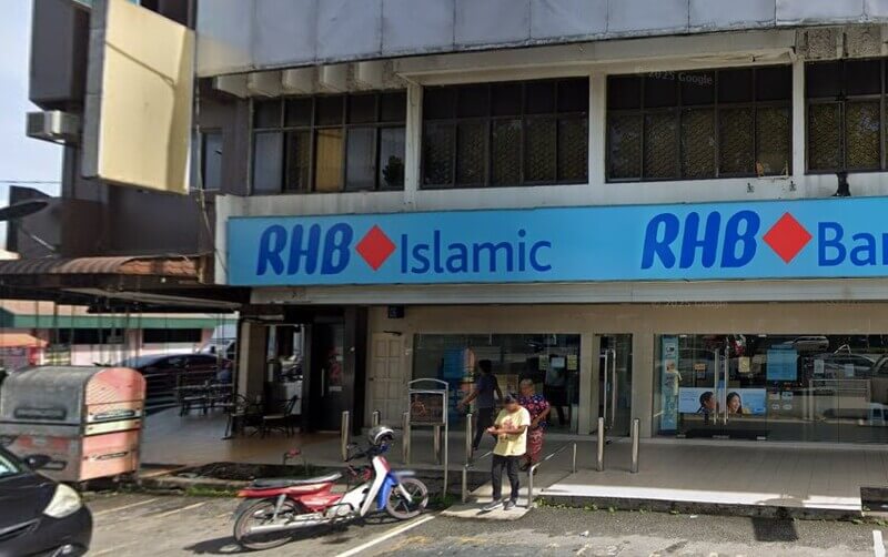 Pandangan hadapan cawangan RHB Islamic dan RHB Bank Tasek dengan papan tanda berwarna biru muda di atas pintu masuk berkaca. Terdapat sebuah motosikal yang diparkir di hadapan bangunan