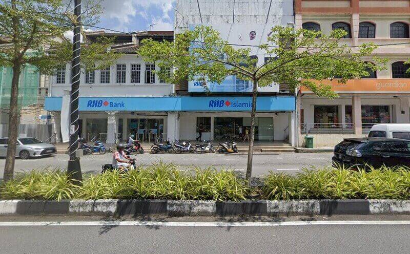 Pemandangan jalan raya pada waktu siang yang menunjukkan deretan kedai termasuk cawangan RHB Bank Taiping RHB Islamic, dan farmasi Guardian