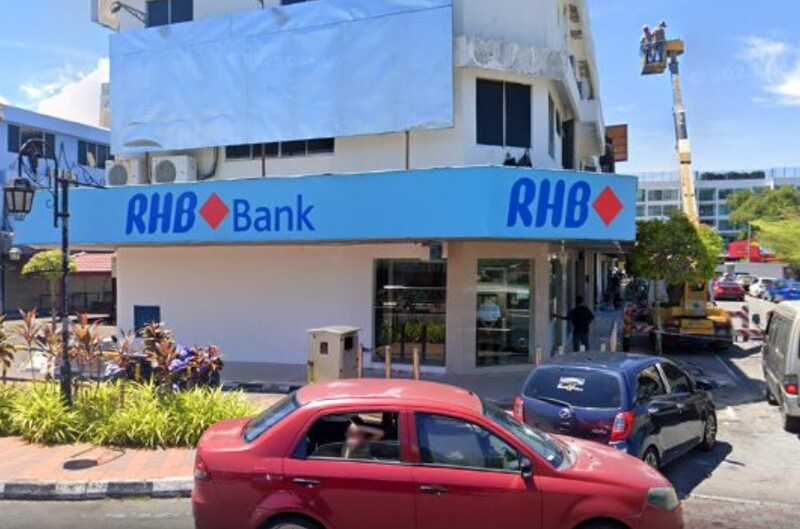 Pandangan luar cawangan RHB Bank Jalan Tun Mustapha di sudut bangunan kedai dua tingkat dengan kereta yang diletakkan di hadapan