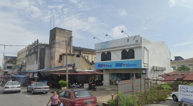 Bangunan cawangan RHB Bank Kuala Kurau dan RHB Islamic dua tingkat di tepi jalan, bersebelahan dengan deretan bangunan lama dan kenderaan yang diletakkan di sekitarnya