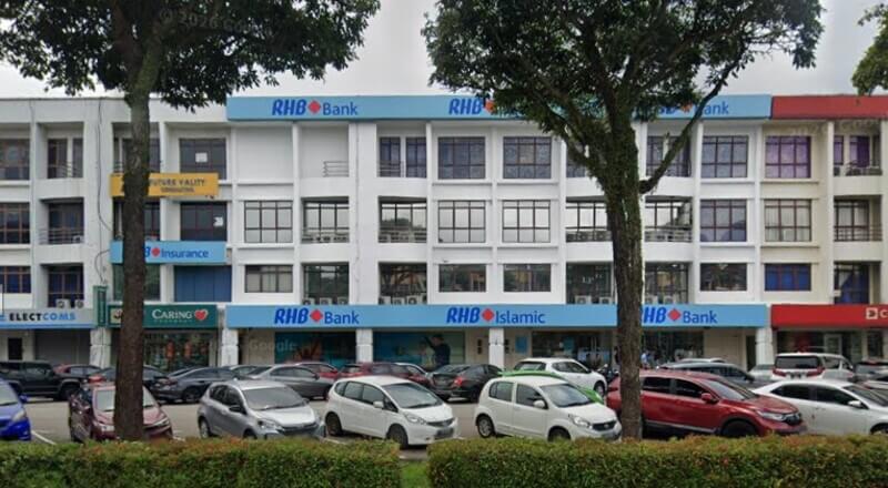 Pemandangan hadapan bangunan kedai bertingkat yang menempatkan cawangan RHB Bank Permas Jaya dan RHB Islamic dengan deretan kereta diletakkan di bahagian hadapan