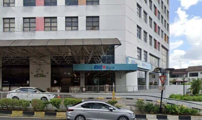 Pandangan luar cawangan RHB Bank di Taman Pelangi, terletak di tingkat bawah bangunan komersial bertingkat dengan sebuah kereta berwarna perak diletakkan di hadapan