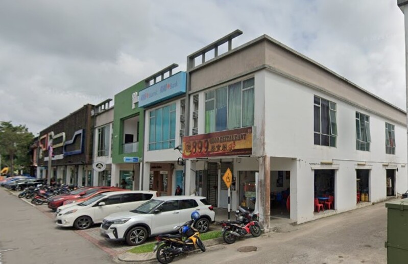 Deretan bangunan kedai dua tingkat yang menempatkan cawangan RHB Bank Bandar Penawar dan Restoran @899, bersama beberapa kenderaan dan motosikal yang diletakkan di hadapannya.