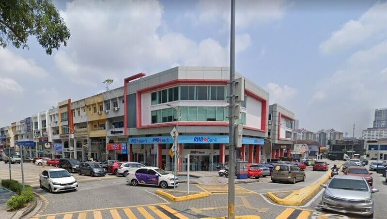 Pandangan dari paras jalan yang menunjukkan bangunan cawangan RHB Bank di Damansara Utama dan RHB Islamic di lot kedai sudut berbilang tingkat, dengan deretan kenderaan diletakkan di hadapannya dan jalan raya di bahagian hadapan