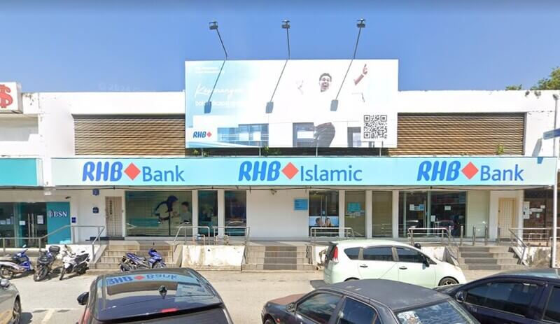 Pandangan hadapan cawangan RHB Bank di Jalan Niaga dan RHB Islamic dengan papan iklan besar di atas bumbung serta kenderaan yang diletakkan di hadapannya