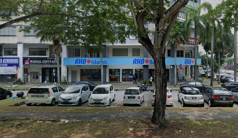 Pandangan hadapan cawangan RHB Bank dan RHB Islamic di deretan kedai Kota Kemuning, Shah Alam, dengan kereta diletakkan di hadapannya.