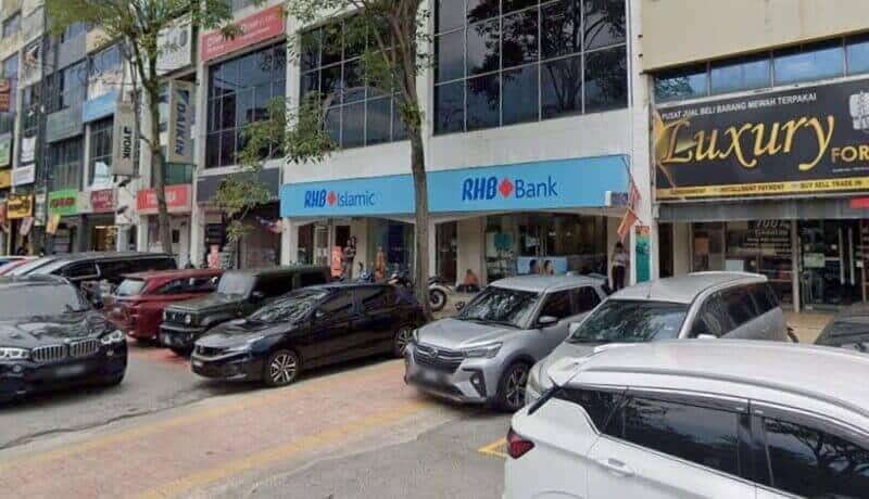 Pandangan luar RHB Bank dan cawangan RHB Islamic yang terletak di Jalan Tg Ampuan Zabedah di Shah Alam, menampilkan hadapan kedai berwarna biru dan kereta yang diletakkan