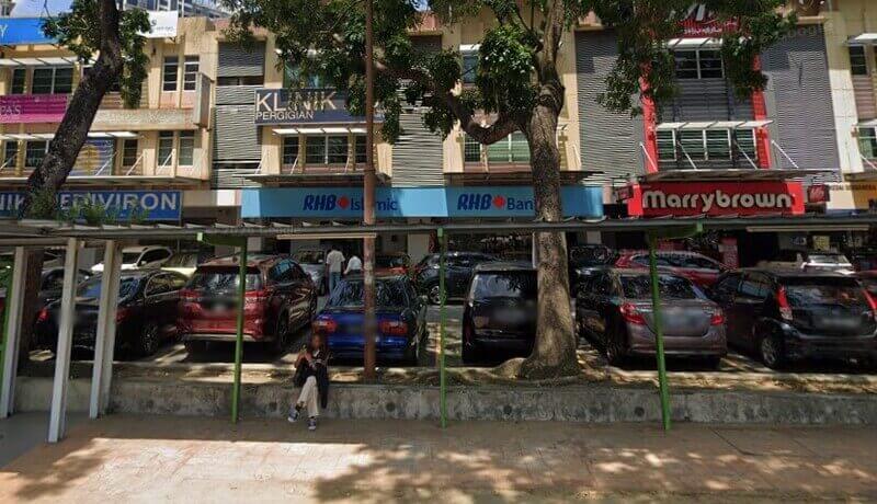 Pemandangan dari luar deretan kedai yang menempatkan cawangan RHB Bank, RHB Islamic, restoran Marrybrown, dan Klinik Pergigian di tepi jalan dengan deretan kereta yang diletakkan di hadapannya.