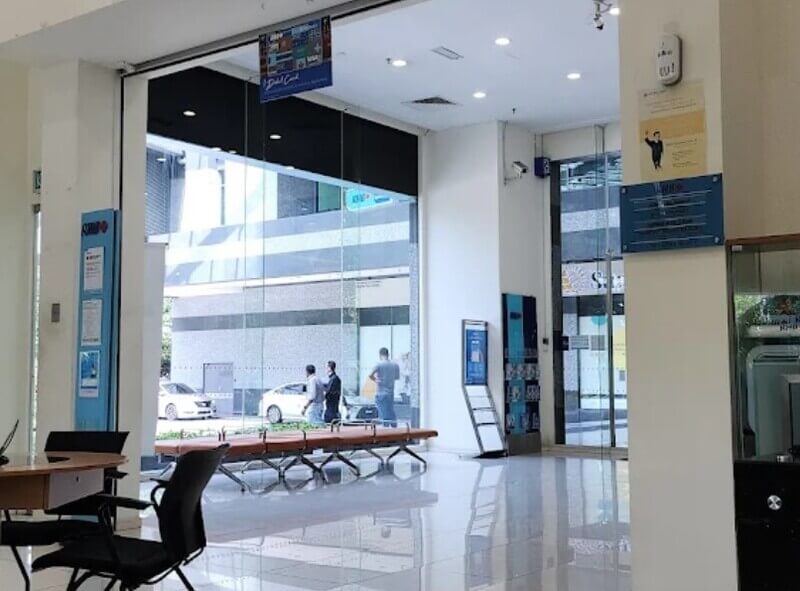 Pandangan dalaman cawangan RHB Bank First Avenue yang terang dan bersih dengan bangku menunggu, cermin kaca gergasi, dan meja perkhidmatan