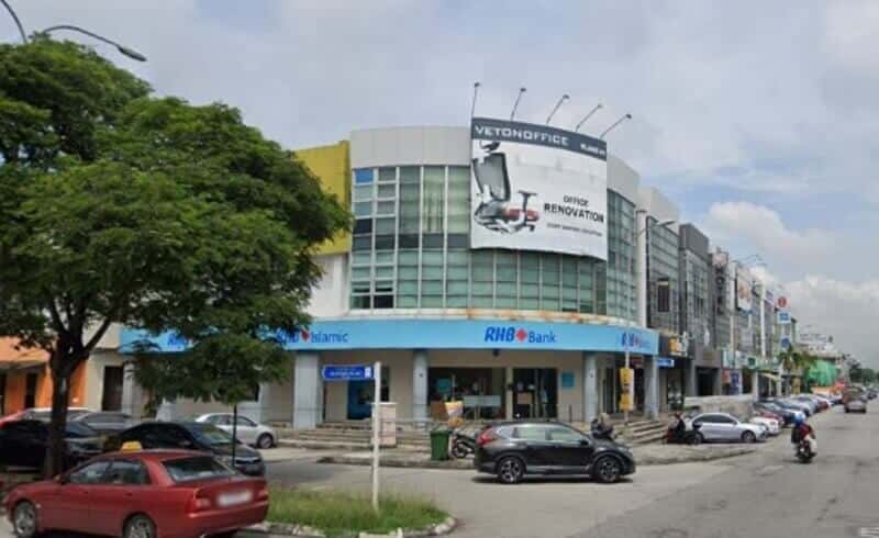 Pandangan sudut RHB Bank Bandar Bukit Tinggi dan cawangan RHB Islamic berwarna biru yang terletak di bangunan komersial bertingkat di Bandar Bukit Tinggi, Klang, dengan kereta diletakkan di hadapan dan iklan "Vetonoffice" yang besar di bahagian hadapan