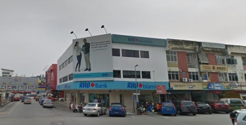 Pemandangan jalan sebuah bank RHB Bank bertingkat putih dan cawangan RHB Islamic di lot sudut di Kajang, menampilkan papan iklan besar di bahagian hadapan dan kereta yang diletakkan di sepanjang kedai