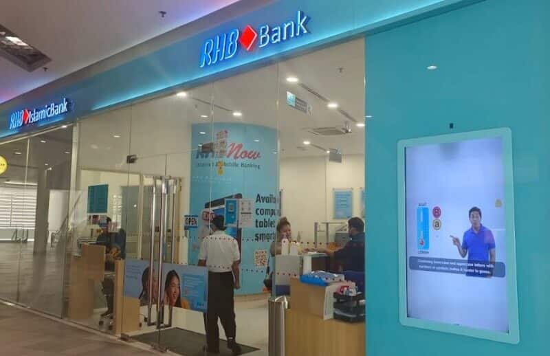 Bahagian luar berkaca di hadapan cawangan RHB Bank dan RHB Islamic Bank di Paradigm Mall, menampilkan papan tanda biru, pencahayaan dalaman yang terang dan skrin paparan digital