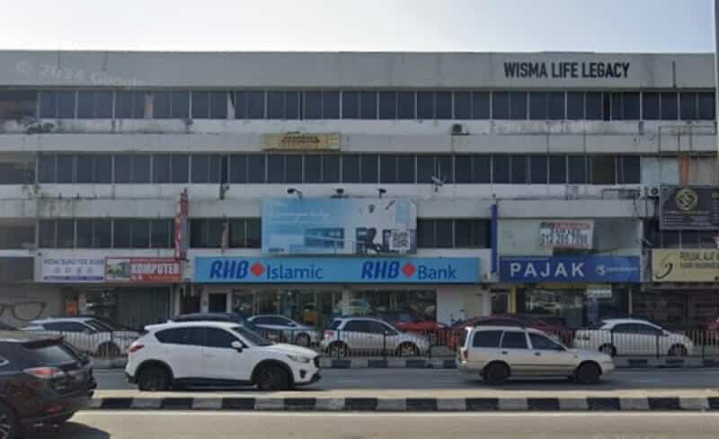 Pemandangan jalan bersudut lebar bangunan komersial bertingkat bernama Wisma Life Legacy, menampilkan RHB Bank cawangan Taman Indah, berserta kedai-kedai lain dan kereta yang diparkir