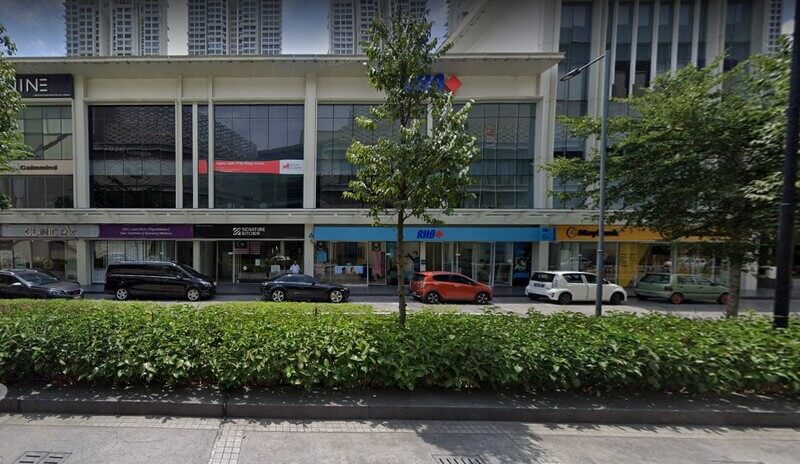Pandangan aras jalan menunjukkan cawangan RHB Bank di Pavilion Bukit Jalil dengan papan tanda biru dan merah, terletak di antara kedai Signature Kitchen dan Maybank. Beberapa buah kereta diletakkan di hadapan kedai