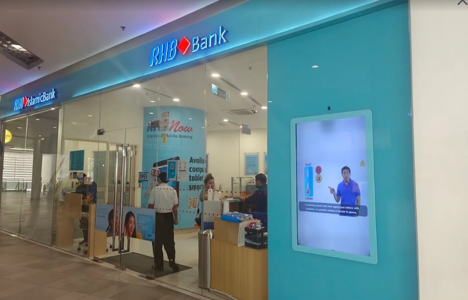 Pandangan hadapan cawangan RHB Bank di Paradigm Malldalam pusat membeli-belah dengan pintu kaca dan paparan skrin digital di sebelah kanan