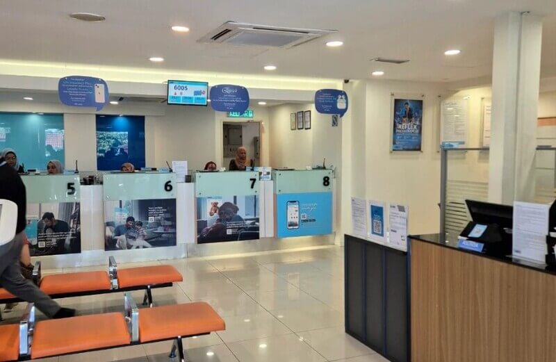 Suasana bahagian dalam cawangan bank RHB di Subang Jaya yang menampilkan kaunter perkhidmatan bernombor dan kerusi menunggu berwarna jingga