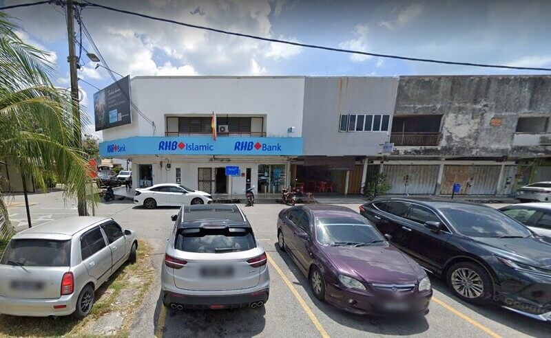 Pandangan hadapan bangunan RHB Bank Tanjung Sepat dan RHB Islamic dua tingkat bernombor warna biru. Kelihatan beberapa buah kenderaan diletakkan di petak tempat letak kereta di hadapan premis di bawah cuaca cerah
